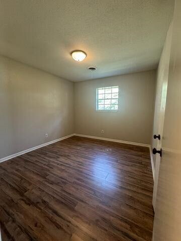 empty room with dark wood-type flooring and a textured ceiling