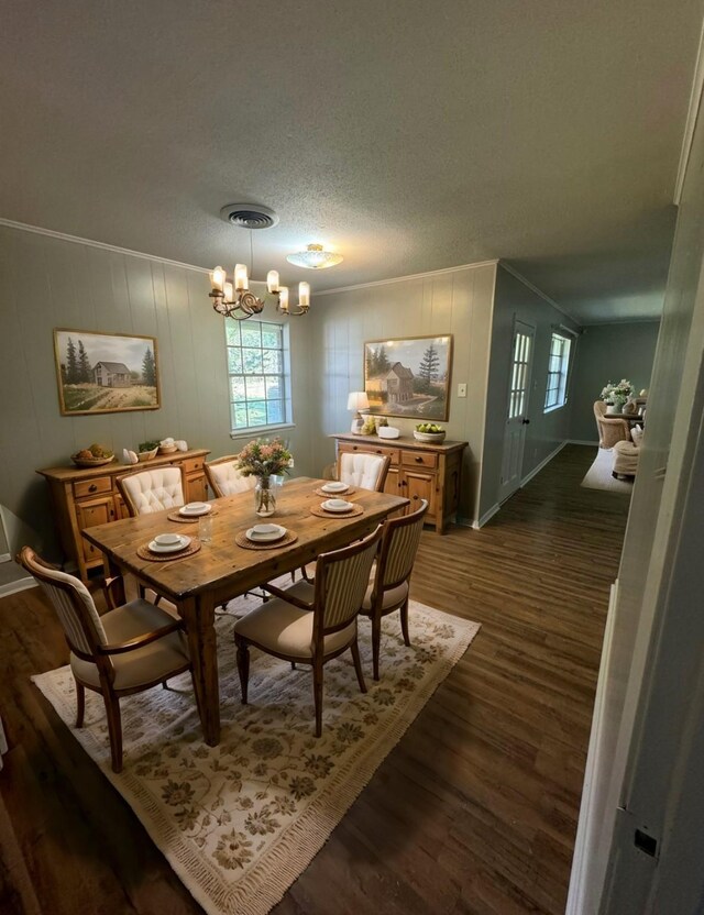 dining area featuring a textured ceiling, dark hardwood / wood-style flooring, an inviting chandelier, and ornamental molding