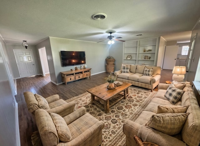 living room featuring ceiling fan, built in features, dark hardwood / wood-style floors, a textured ceiling, and ornamental molding