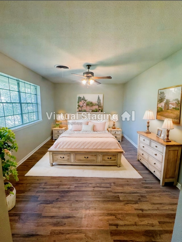 bedroom featuring ceiling fan, dark hardwood / wood-style flooring, and a textured ceiling