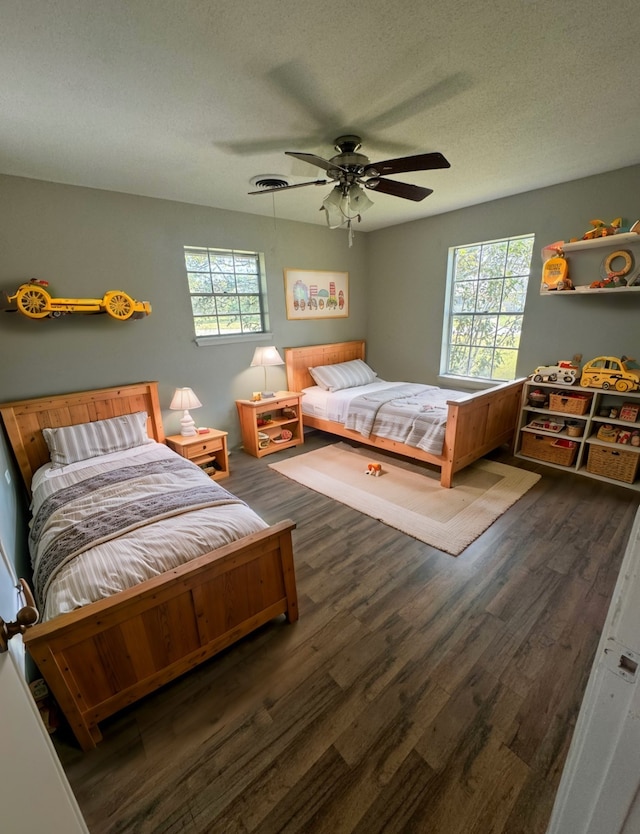 bedroom featuring ceiling fan, dark hardwood / wood-style floors, a textured ceiling, and multiple windows