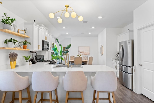 kitchen featuring a breakfast bar, sink, white cabinetry, kitchen peninsula, and black appliances