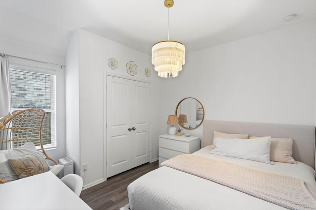 bedroom with a notable chandelier and dark wood-type flooring