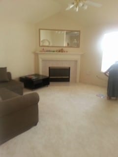 carpeted living room with ceiling fan and lofted ceiling