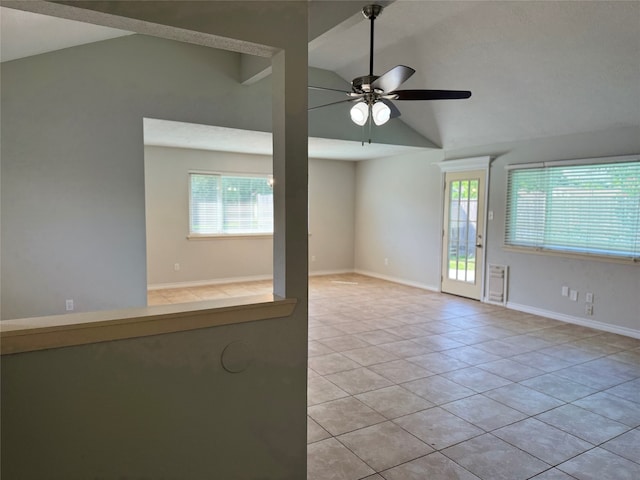 tiled empty room featuring a wealth of natural light, ceiling fan, and vaulted ceiling