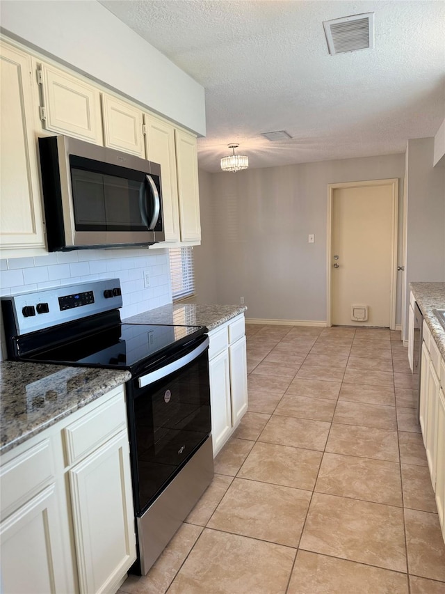 kitchen with decorative backsplash, light tile patterned flooring, stainless steel appliances, and a textured ceiling