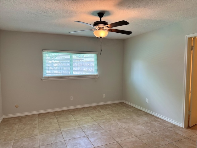 empty room with ceiling fan, light tile patterned flooring, and a textured ceiling