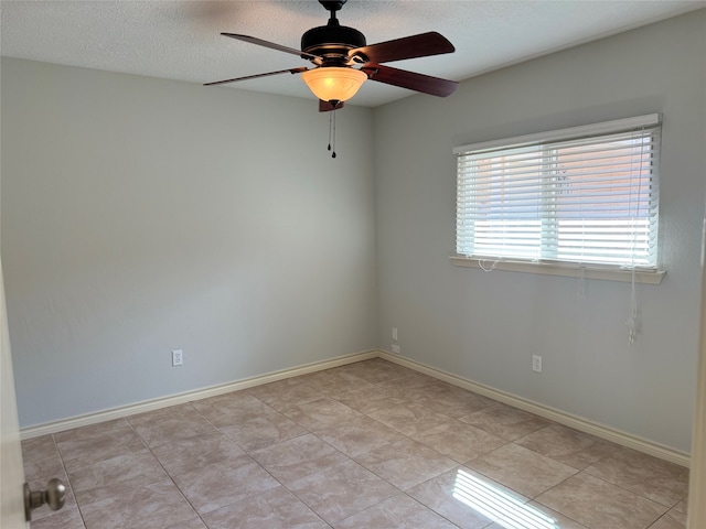 spare room featuring ceiling fan, light tile patterned floors, and a textured ceiling