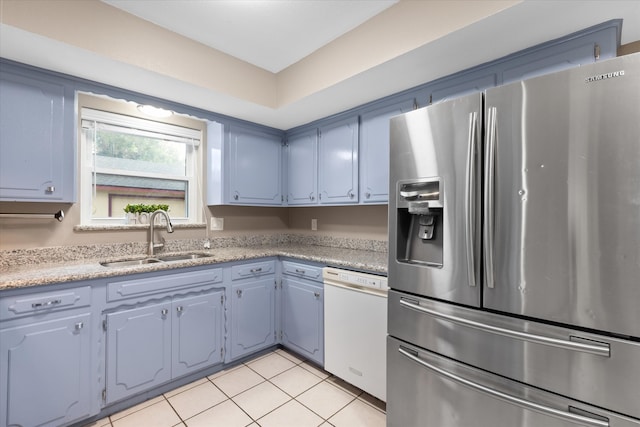 kitchen with stainless steel refrigerator with ice dispenser, white dishwasher, sink, light tile patterned floors, and blue cabinetry