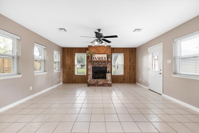 unfurnished living room with wooden walls, light tile patterned floors, and a wealth of natural light