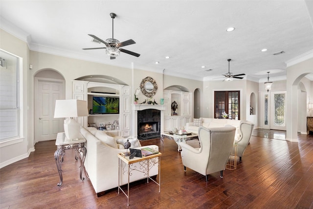 living room featuring a premium fireplace, ceiling fan, crown molding, and dark hardwood / wood-style floors