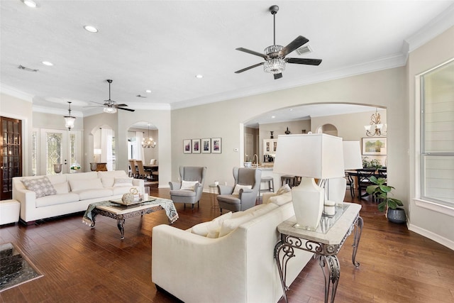 living room featuring ceiling fan with notable chandelier, dark wood-type flooring, french doors, and ornamental molding