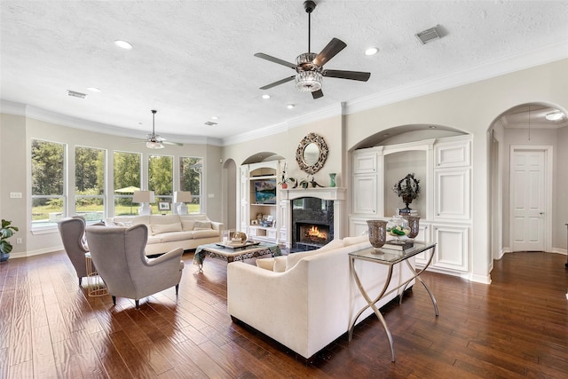 living room with ornamental molding, a textured ceiling, ceiling fan, and a fireplace