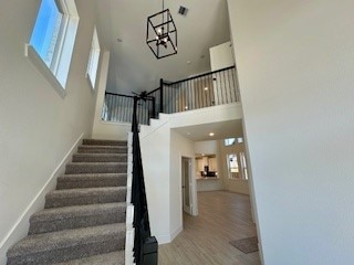 stairs with a towering ceiling and hardwood / wood-style flooring