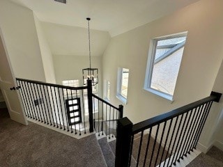 staircase featuring lofted ceiling, carpet floors, and a chandelier