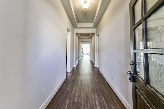 hall featuring a raised ceiling and dark wood-type flooring