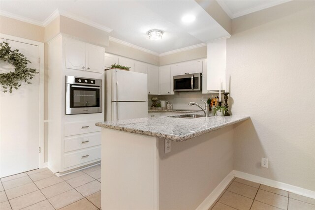 kitchen featuring sink, kitchen peninsula, stainless steel appliances, white cabinets, and light stone counters