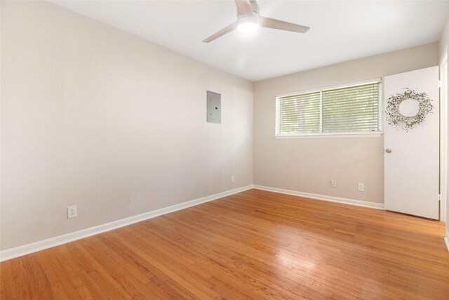 empty room featuring electric panel, light hardwood / wood-style floors, and ceiling fan