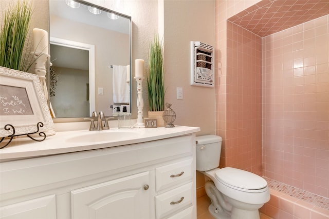 bathroom with vanity, toilet, tile patterned floors, and tiled shower