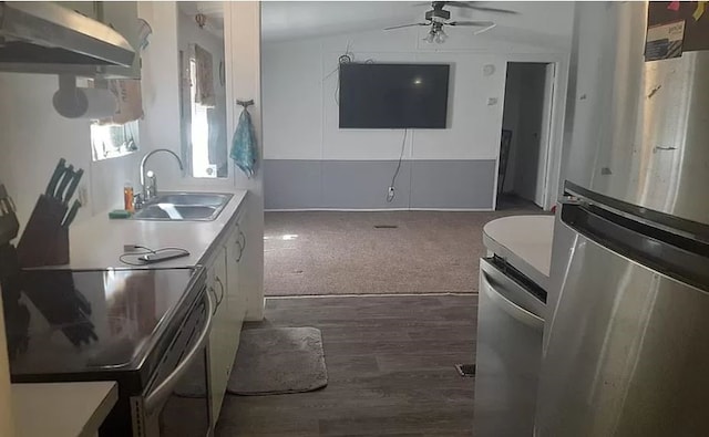 kitchen with lofted ceiling, dark colored carpet, ceiling fan, sink, and wall chimney range hood