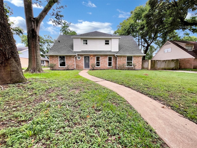 view of front of home with a front yard, fence, brick siding, and a shingled roof