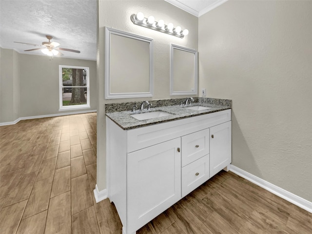 bathroom featuring vanity, a textured ceiling, ceiling fan, and ornamental molding