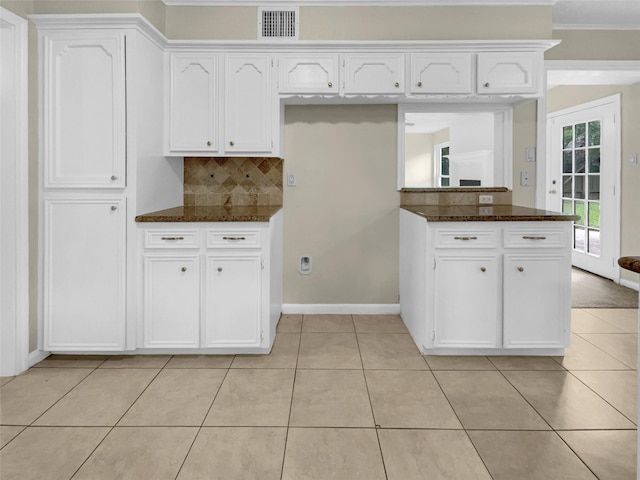 kitchen featuring tasteful backsplash, dark stone countertops, white cabinets, and light tile patterned floors