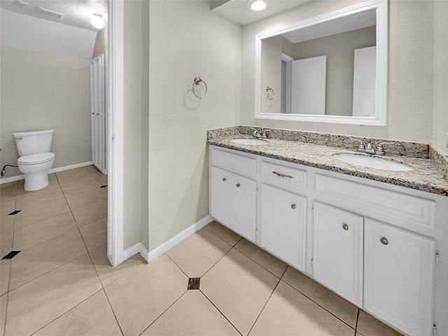 bathroom with tile patterned floors, vanity, a textured ceiling, and toilet