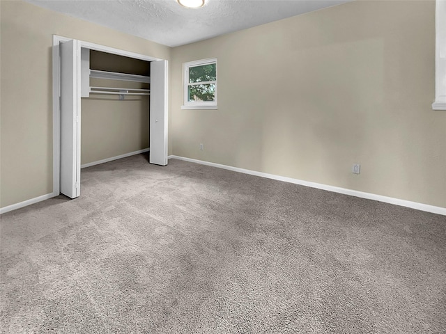 unfurnished bedroom featuring a textured ceiling, light carpet, and a closet