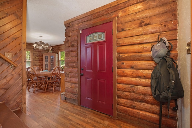 entryway with log walls, a notable chandelier, and hardwood / wood-style floors