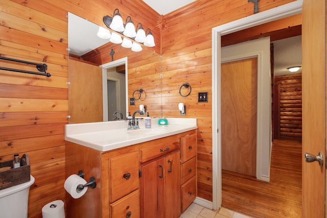 bathroom featuring vanity, hardwood / wood-style floors, toilet, and wooden walls