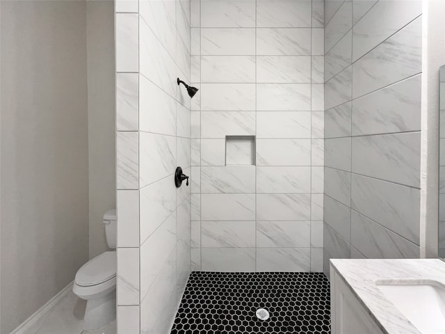 bathroom with toilet, vanity, and a tile shower