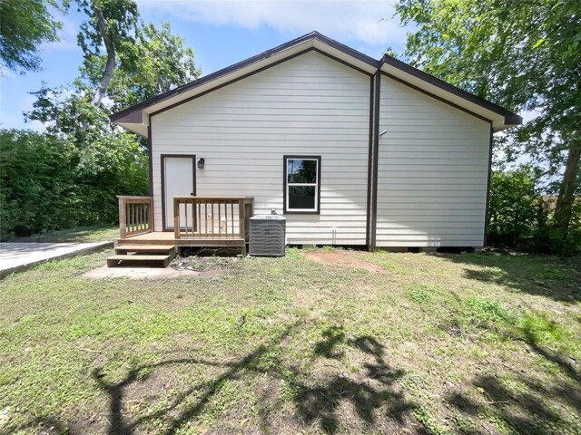 back of house featuring central air condition unit, a wooden deck, and a lawn