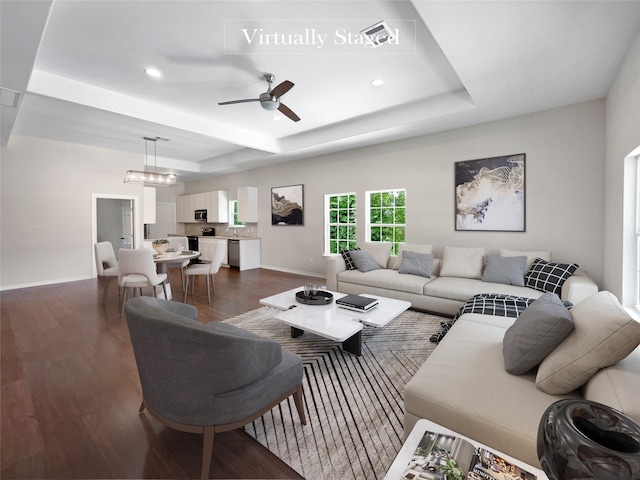 living room featuring ceiling fan with notable chandelier and dark hardwood / wood-style flooring