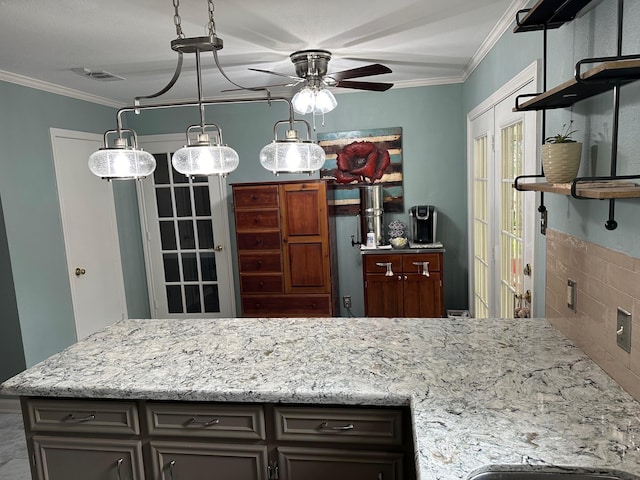 kitchen with ceiling fan, dark brown cabinets, light stone countertops, and ornamental molding