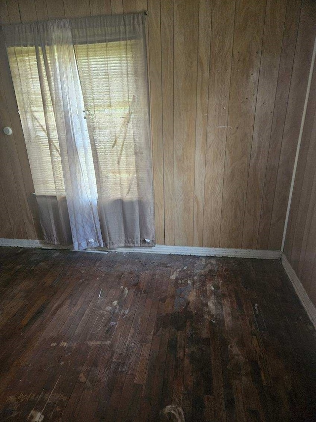 empty room featuring dark wood-type flooring and wood walls