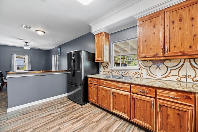 kitchen featuring light hardwood / wood-style flooring, ceiling fan, tasteful backsplash, black refrigerator, and sink