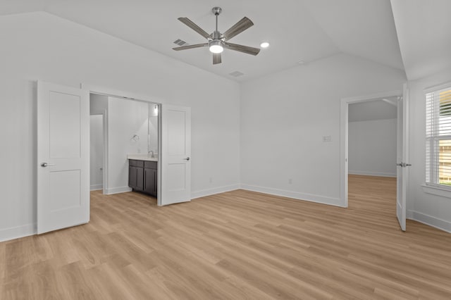 unfurnished bedroom with lofted ceiling, ceiling fan, light wood-type flooring, ensuite bathroom, and sink