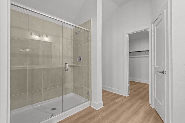 bathroom with lofted ceiling, wood-type flooring, and a shower with shower door