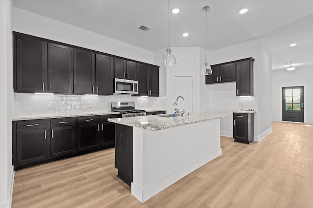 kitchen with sink, a kitchen island with sink, stainless steel appliances, and light hardwood / wood-style floors