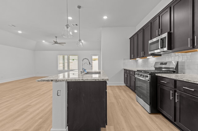 kitchen with a center island with sink, sink, pendant lighting, appliances with stainless steel finishes, and light hardwood / wood-style floors