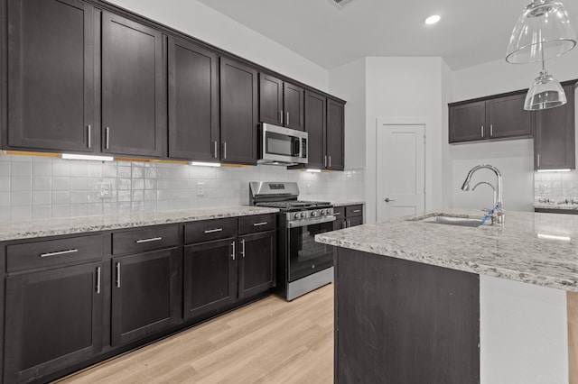 kitchen with stainless steel appliances, sink, dark brown cabinetry, light wood-type flooring, and tasteful backsplash