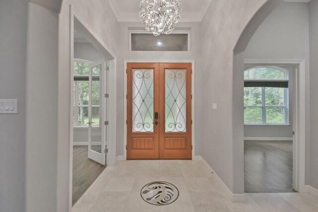 foyer entrance featuring a notable chandelier, french doors, light tile flooring, and a wealth of natural light