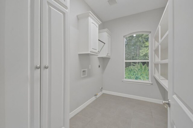 clothes washing area featuring cabinets, hookup for a gas dryer, light tile floors, and electric dryer hookup