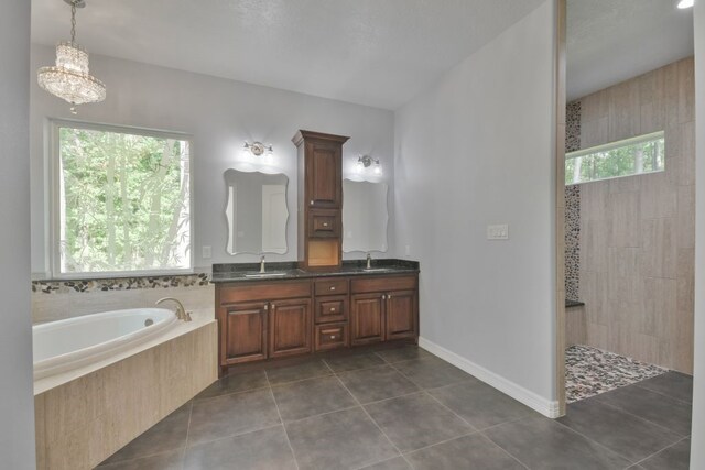 bathroom featuring a notable chandelier, double sink vanity, tile floors, and tiled tub