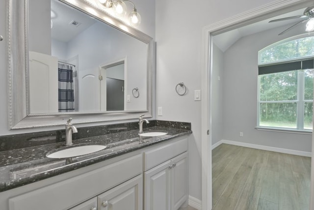 bathroom with vaulted ceiling, oversized vanity, ceiling fan, wood-type flooring, and double sink