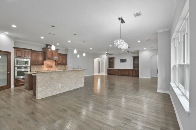 kitchen featuring stainless steel appliances, a spacious island, hanging light fixtures, ceiling fan, and tasteful backsplash