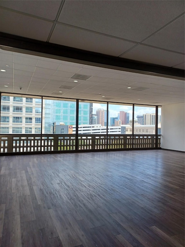 empty room with hardwood / wood-style flooring, a wall of windows, and a wealth of natural light