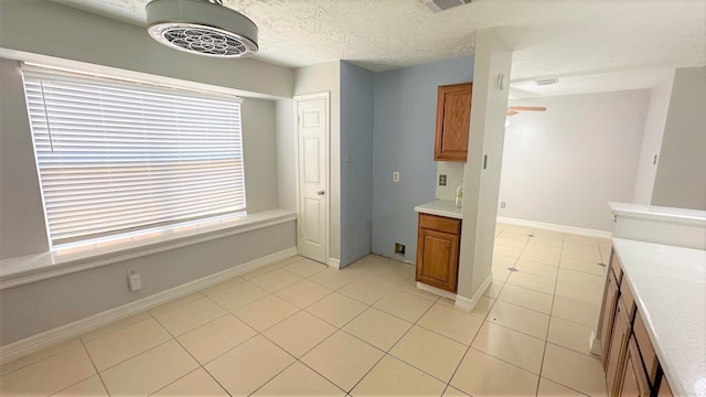 kitchen with a textured ceiling, light tile patterned floors, and ceiling fan