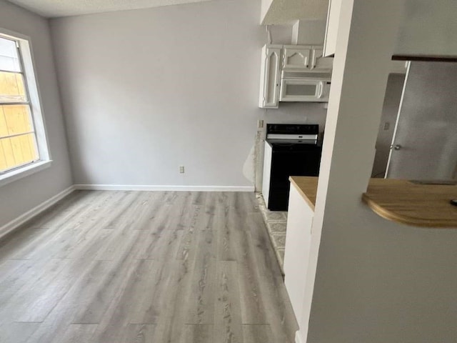 kitchen with range, white cabinetry, and wood-type flooring